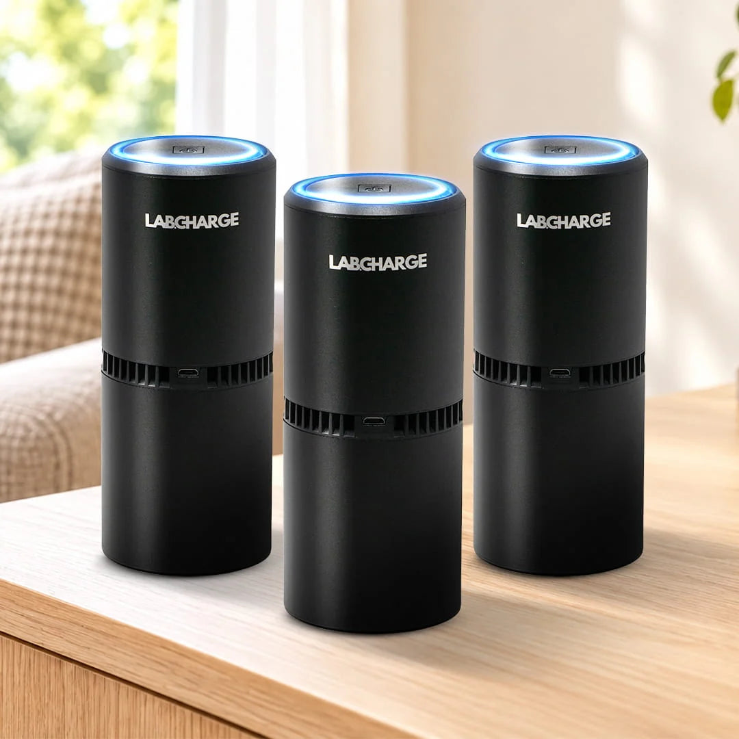 3 black Labcharge air purifiers on a light oak table in a neutral living room